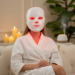 Woman in white robe wearing LED face mask in luxury spa setting