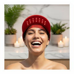Woman wearing LumiVida Red Light Therapy Cap with glowing red LEDs in a luxury wellness spa setting, smiling confidently